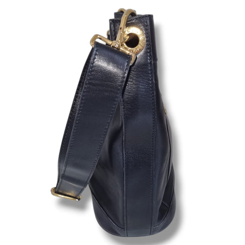 Sac Céline vintage noir en cuir lisse avec intérieur rouge et détails dorés porté épaule
