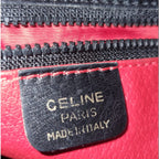 Sac Céline vintage noir en cuir lisse avec intérieur rouge et détails dorés porté épaule
